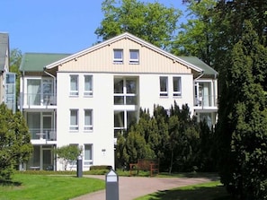 A multi-story residential building with a flat roof, large windows, and a central entrance.