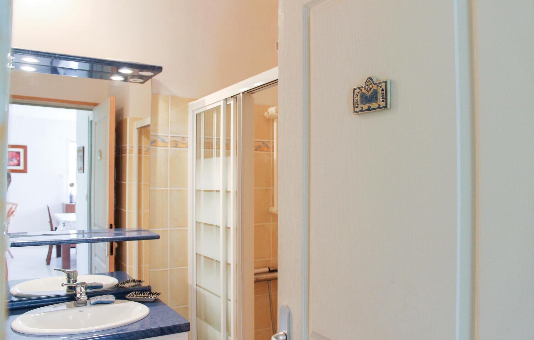 Une salle de bain avec un double lavabo, un miroir et un espace douche.