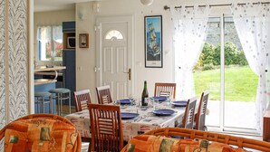 A dining area with a table set for six, chairs, a ceiling fan, a door, and a window with curtains. - 3 bedroom gorgeous home in Lamballe-Armor (Lamballe-Armor)