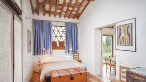 A bedroom with a wooden ceiling, a bed, a desk, and a chair.