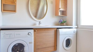 A compact laundry area with two washing machines, a sink, and wooden cabinets. - Gorgeous home in Skjern with sauna (Skjern)