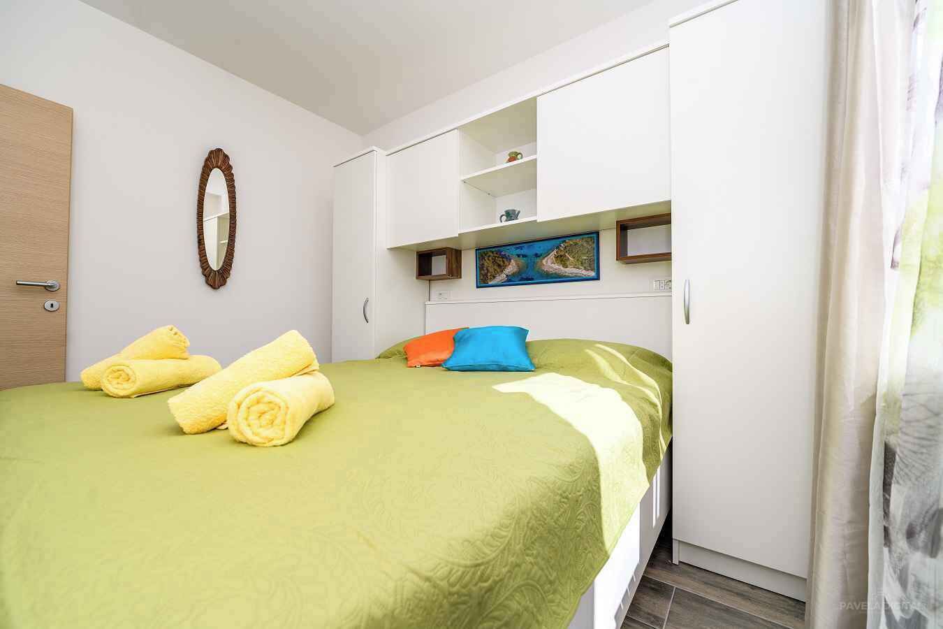 Une chambre d’hôtel avec un lit, une armoire, un miroir et un tableau au mur.