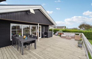 En uteplats med ett bord och stolar, en soffa och en grill.