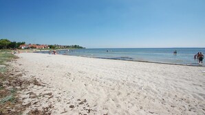 Una playa arenosa con gente nadando y paseando por la orilla.