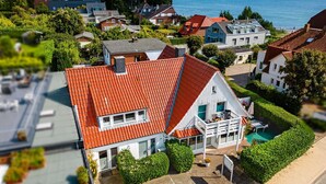 Uma casa com telhado de telhas vermelhas, varanda e jardim.