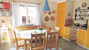 A dining area with a round table, wooden chairs, a blue hanging light, and a window with curtains. - Awesome home in Värnamo with kitchen (Värnamo)