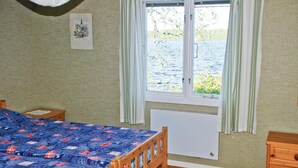 A bedroom with a bed, a window with a view of a body of water, a radiator, and a wooden nightstand. - Awesome home in Värnamo with kitchen (Värnamo)