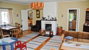 A cozy living room with a fireplace, a dining area with a table and chairs, and a sofa. - Awesome home in Värnamo with kitchen (Värnamo)