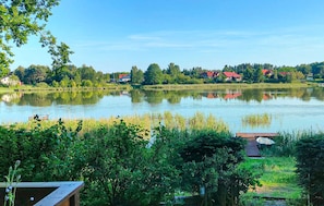 A lake with a dock, surrounded by greenery and houses in the background.