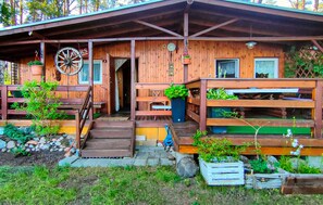 A wooden cabin with a porch, a wheel, and a small garden. - Cozy home in Ostróda with house sea view (Ostróda)