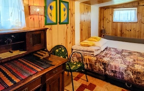 Une pièce en bois avec un lit, un bureau et une chaise. Deux tableaux encadrés sont accrochés au mur.