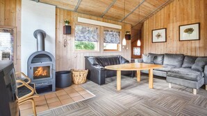 A cozy cabin interior with a wood-burning stove, leather sofa, and a dining table. - Nice home in Hejls with WiFi (Hejls)