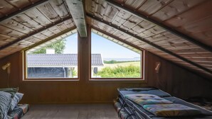 A small attic bedroom with a sloped ceiling, two windows offering a view of the countryside, and a bed with colorful bedding. - Nice home in Hejls with WiFi (Hejls)