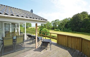 A covered outdoor patio with a table and chairs, a wooden deck, and a view of a green landscape. - Nice home in Hejls with WiFi (Hejls)