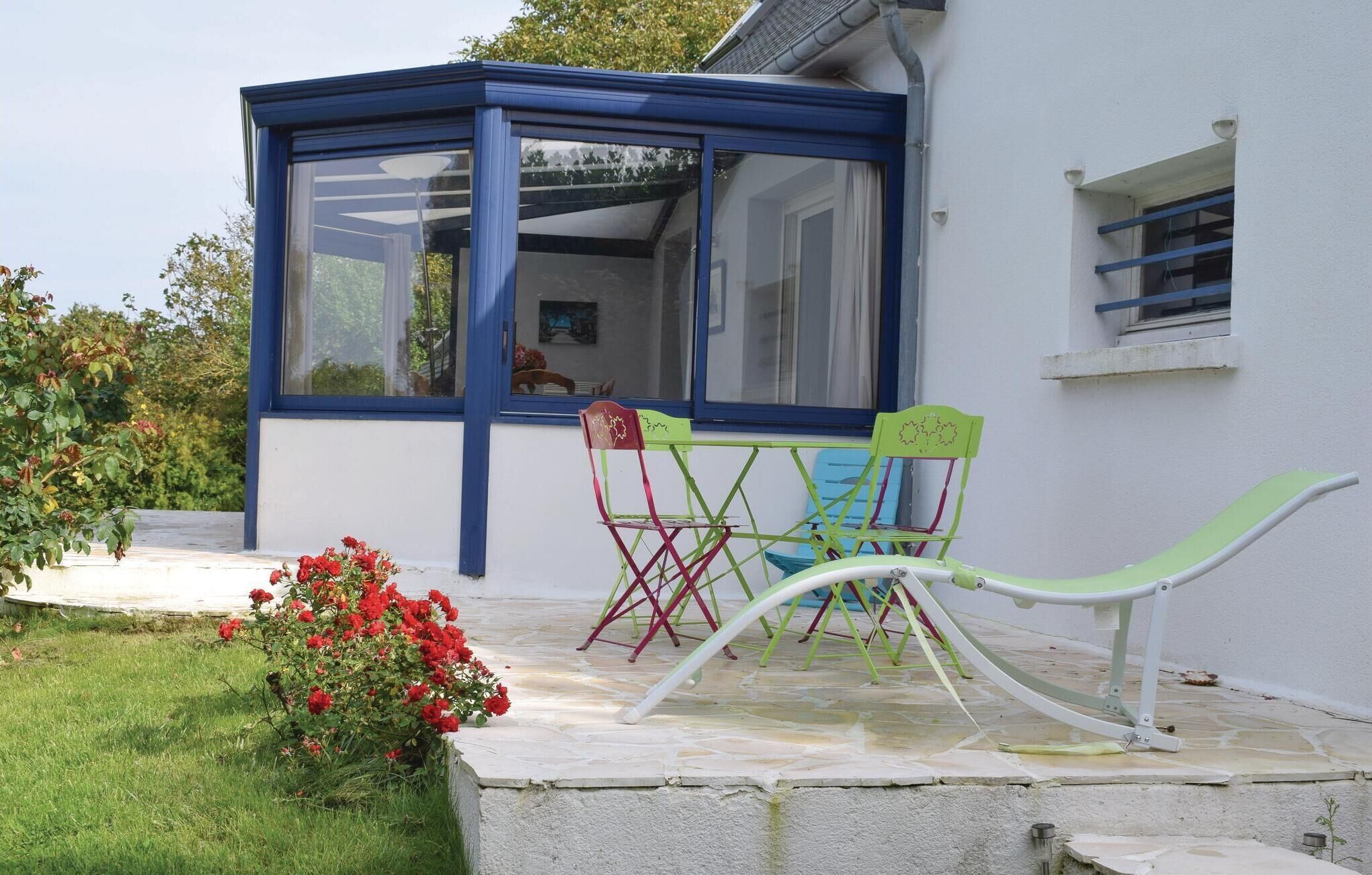 A covered patio with a blue frame, a small table, and colorful chairs.