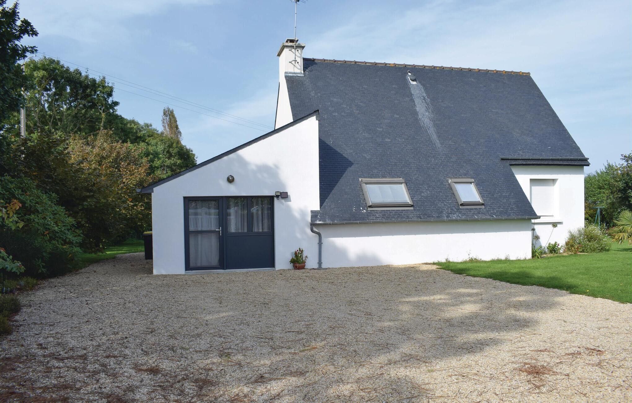 A two-story house with a gravel driveway, a small garden, and a clear sky.