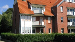 A multi-story residential building with a red-tiled roof, white-framed windows, and balconies. - Ressing Vacation Rental - - Ressing Vacation Rental (Brodersby)