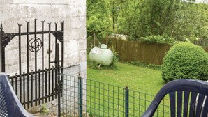 Un'area esterna recintata con prato verde, una recinzione in metallo e un serbatoio verde di grandi dimensioni.