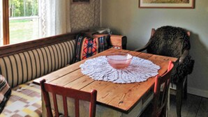 A wooden dining table with a pink glass bowl and a lace doily, surrounded by wooden chairs.