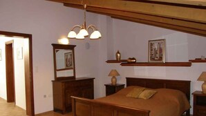 Un dormitorio con una cama de madera, una mesita de noche, un aparador, un espejo y una lámpara colgante.