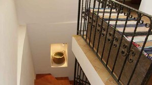 Una escalera de madera con barandilla de metal y un pequeño estante con un cuenco.