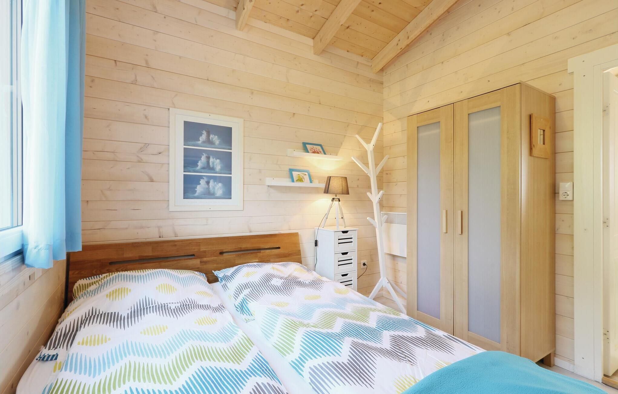 A wooden-paneled bedroom with a bed, a wardrobe, and a framed picture on the wall.