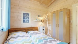 Ein Schlafzimmer mit Holzwänden, einem Bett, einem Kleiderschrank und einem gerahmten Bild an der Wand.