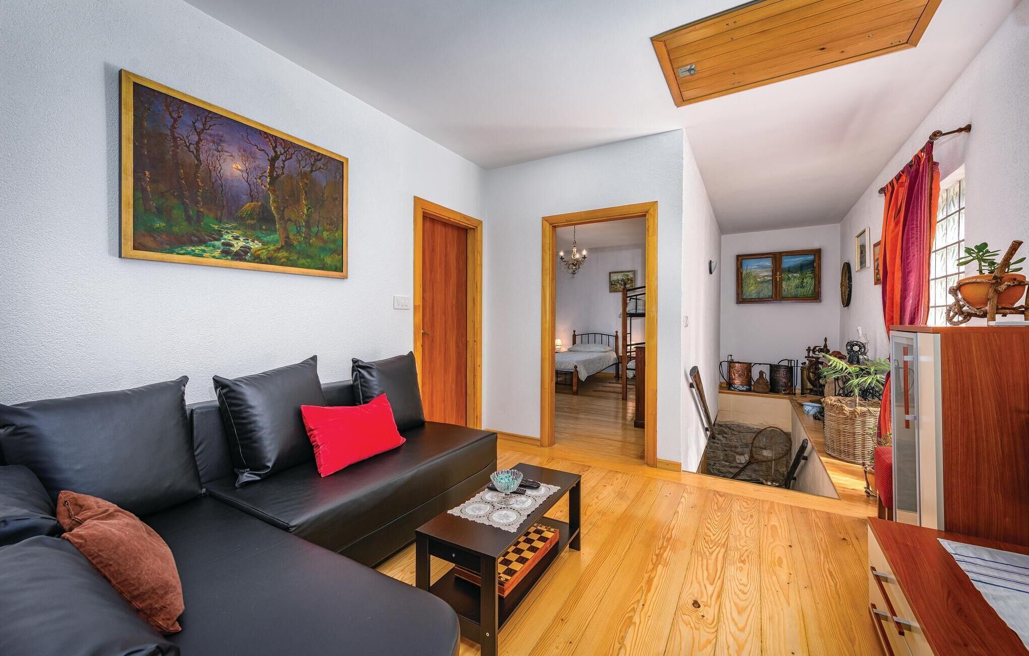 A modern living room with a black sofa, wooden coffee table, and a painting on the wall.