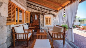 A cozy outdoor seating area with wooden furniture and stone walls. - Lovely home in Kozljak (Kozljak)