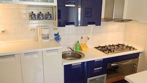 A modern kitchen with white cabinets, a gas stove, an oven, and a microwave. - Holiday apartment with internet access (Valbandon)
