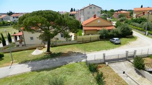 A residential area with houses, a tree, a paved road, and a car parked on the street. - Holiday apartment with internet access (Valbandon)
