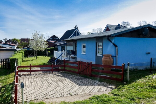Una propiedad residencial con entrada pavimentada, un portón rojo y una casa azul.
