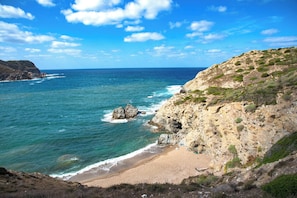 Eine Küstenlandschaft mit Strand, felsigen Klippen und dem Meer.