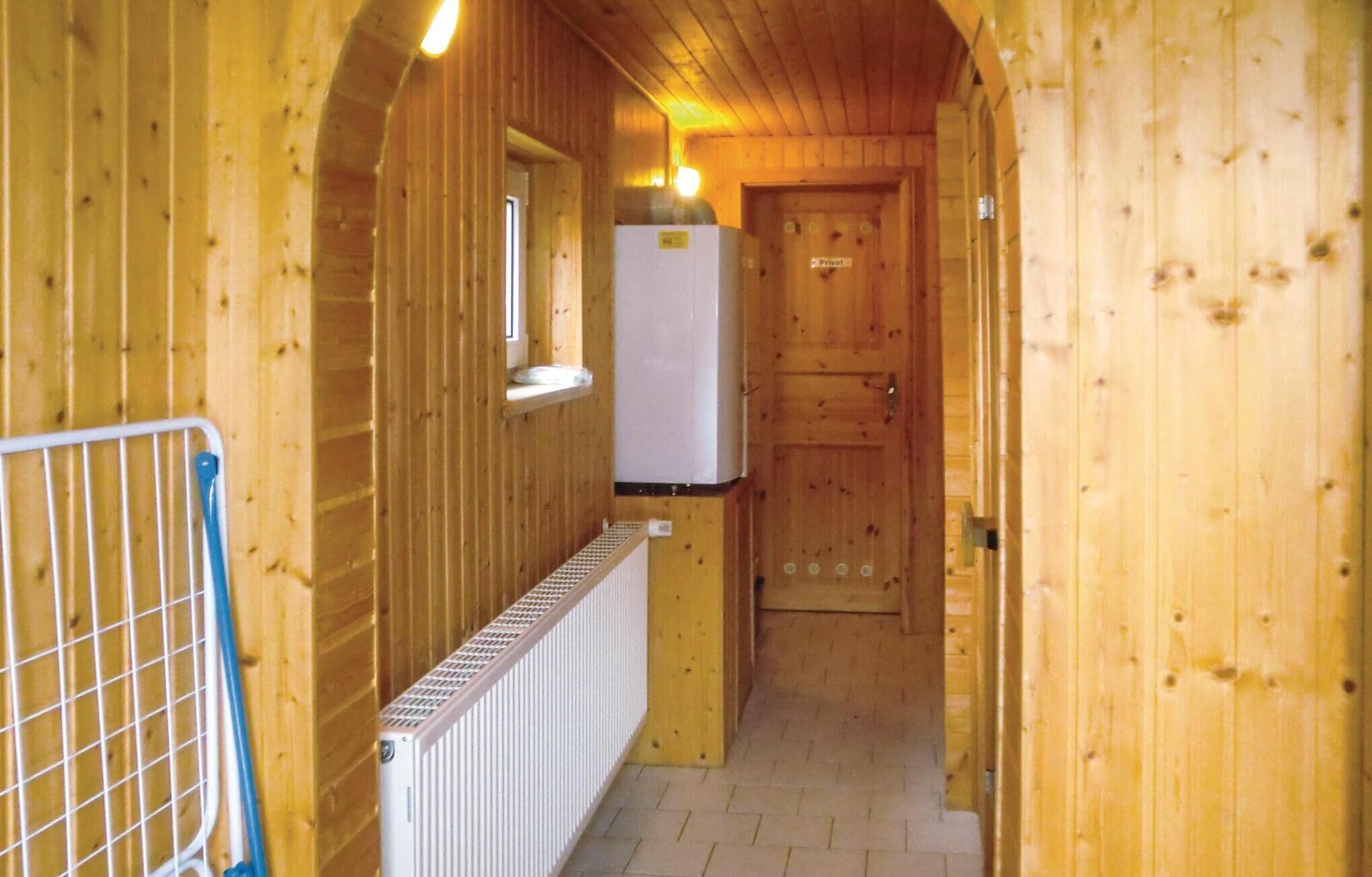 A narrow wooden corridor with a white radiator, a blue metal gate, and a white refrigerator.
