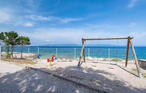A playground with swings and a bench, a fenced area, and a view of the sea. - Stunning apartment in Labin with swimming pool (Labin)