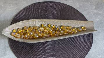 A dark textured circular mat with a metallic object containing yellowish beads.
