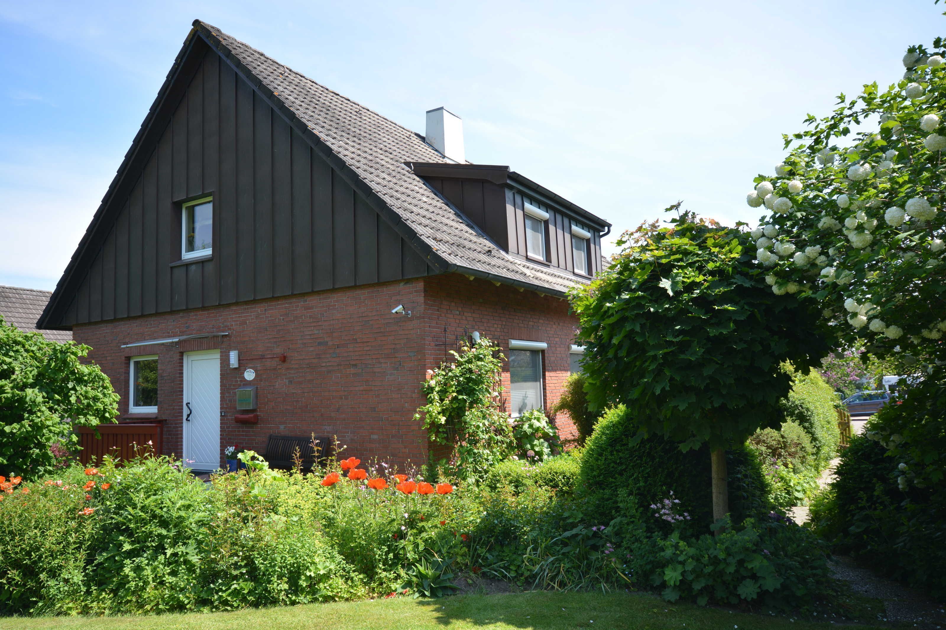 Een huis met twee verdiepingen, een schuin dak en een gevel van baksteen, met een voordeur.
