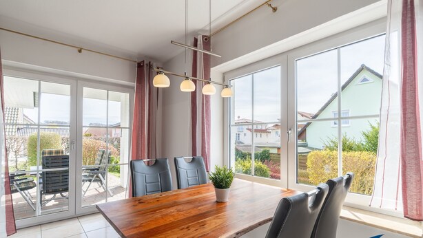 A dining area with a wooden table, black chairs, and a potted plant. - Apartment (ap.) Whg. 01 Gartenstraße - Garden 01 (Heringsdorf)