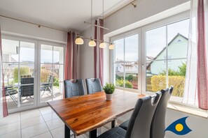 Ein Essbereich mit einem Holztisch, schwarzen Stühlen und einem Topf mit einer Pflanze.
