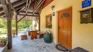 A covered outdoor area with stone flooring, wooden benches, a wooden door, and a stone barrel. - Beautiful home in Lukovdol with sauna (Lukovdol)