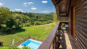 A wooden cabin with a balcony overlooking a swimming pool and a lush green landscape. - Beautiful home in Lukovdol with sauna (Lukovdol)
