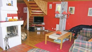 Ein gemütliches Wohnzimmer mit Kamin, Fernseher und Möbeln in Karomuster.