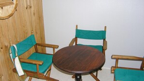 Ein runder Holztisch mit dunkler Oberfläche, umgeben von vier Holzsesseln mit Sitz- und Rückenlehnen in Türkisblau.