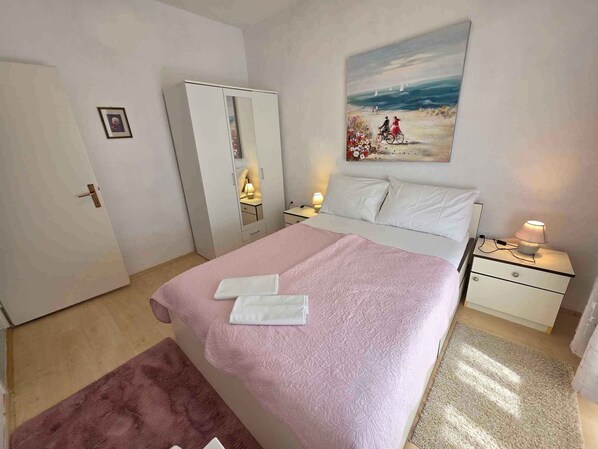 A bedroom with a bed, a nightstand, a dresser, and a painting on the wall.