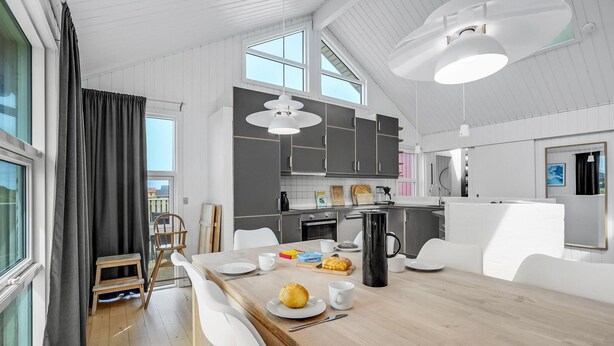 A modern kitchen with white cabinets, a wooden dining table, and a breakfast setup. - Gorgeous home in Thisted with sauna (Thisted)