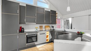 A modern kitchen with dark grey cabinets, a built-in oven, and a large island with a sink. - Gorgeous home in Thisted with sauna (Thisted)