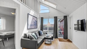 A modern living room with a grey sofa, a small round table, and a TV mounted on the wall. - Gorgeous home in Thisted with sauna (Thisted)
