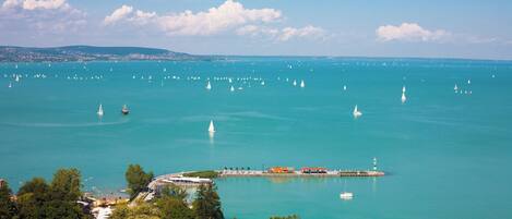 A coastal town with a marina filled with sailboats, a lighthouse, and a pier with buildings.