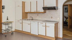 A modern kitchen with white cabinets, a stainless steel sink, and a built-in range hood. - Ferienwohnung mit Lift (Rauris)
