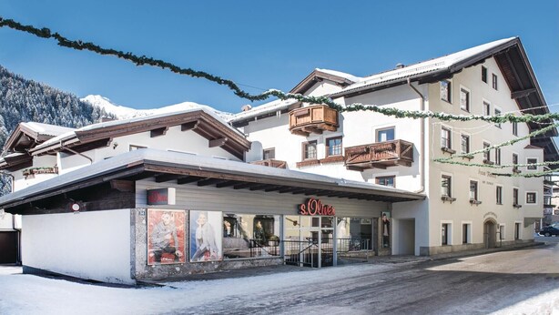 A hotel with a traditional Alpine architectural style, featuring wooden balconies and a snow-covered roof. - Ferienwohnung mit Lift (Rauris)